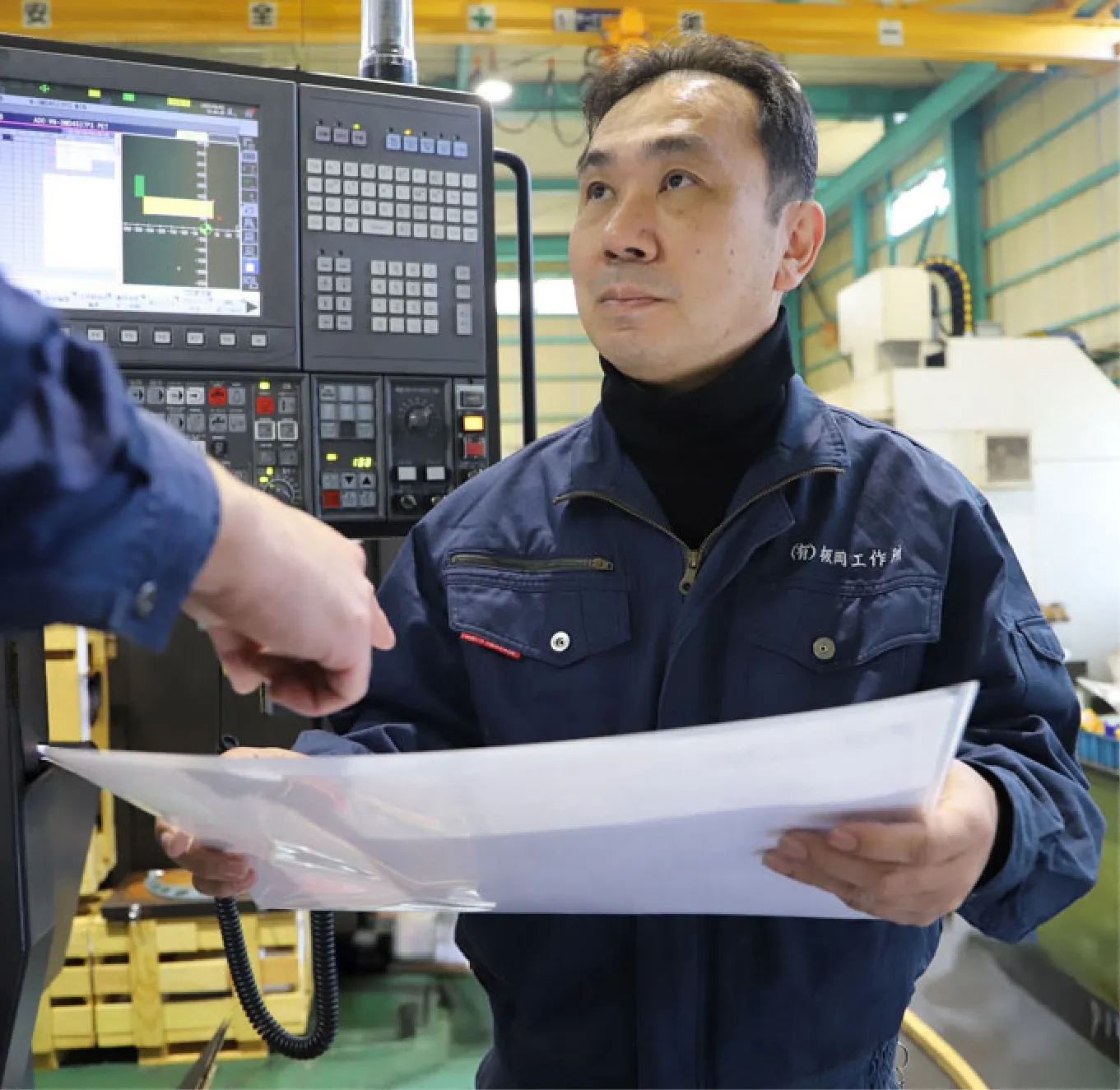 工場で図面を確認する板岡工作所のスタッフ