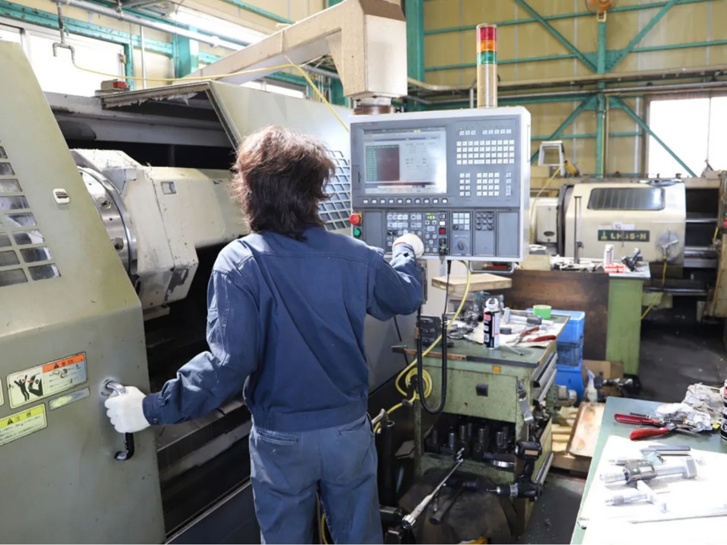 工場でNC旋盤を操作する作業者